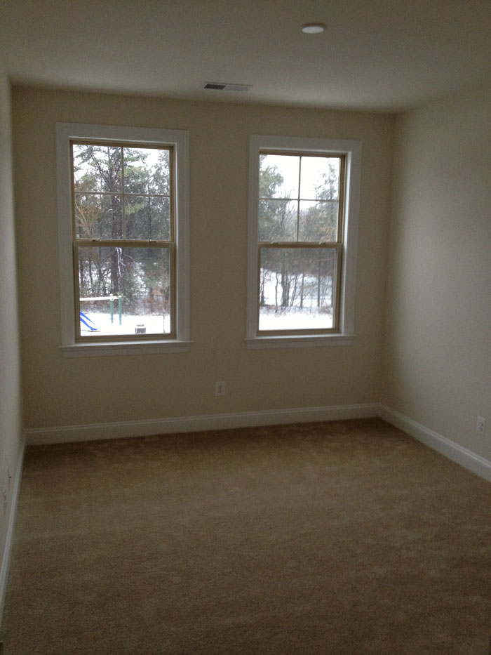 The original room with beige carpet and walls