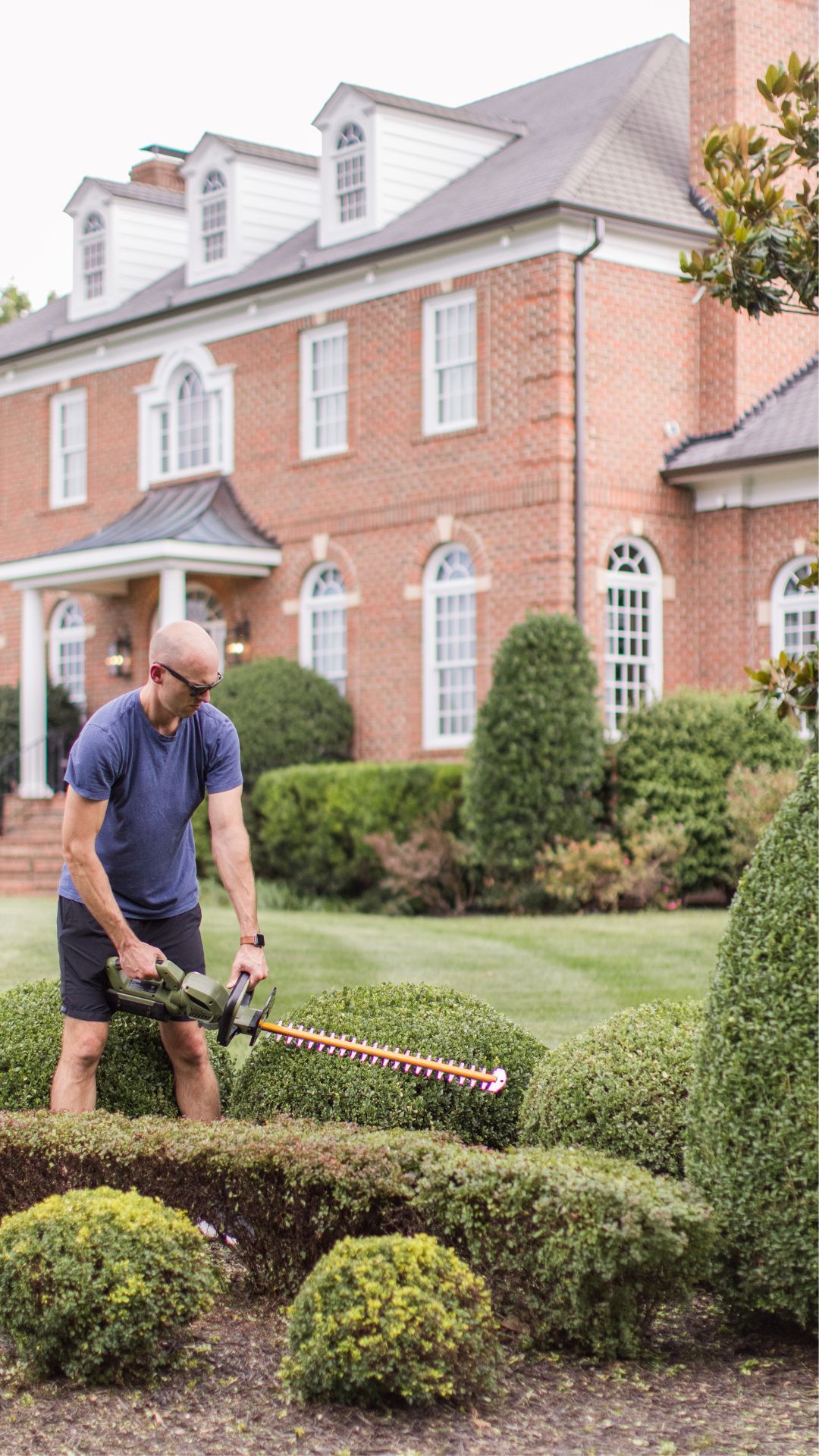 The Green Machine Hedge Trimmer cutting the bushes in front of The Arched Manor