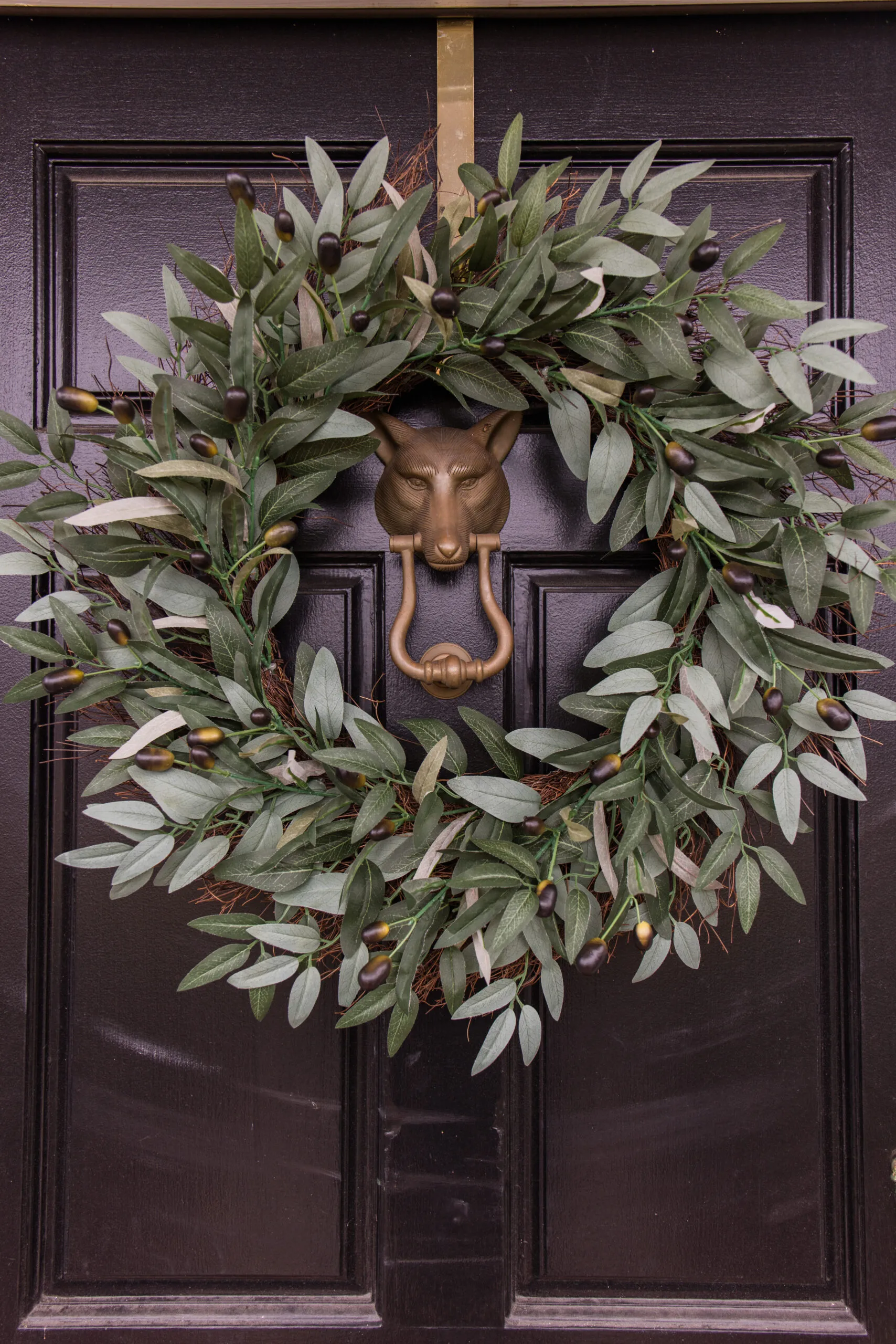Arched manor spring front door styling, close up image of faux olive wreath on black front door