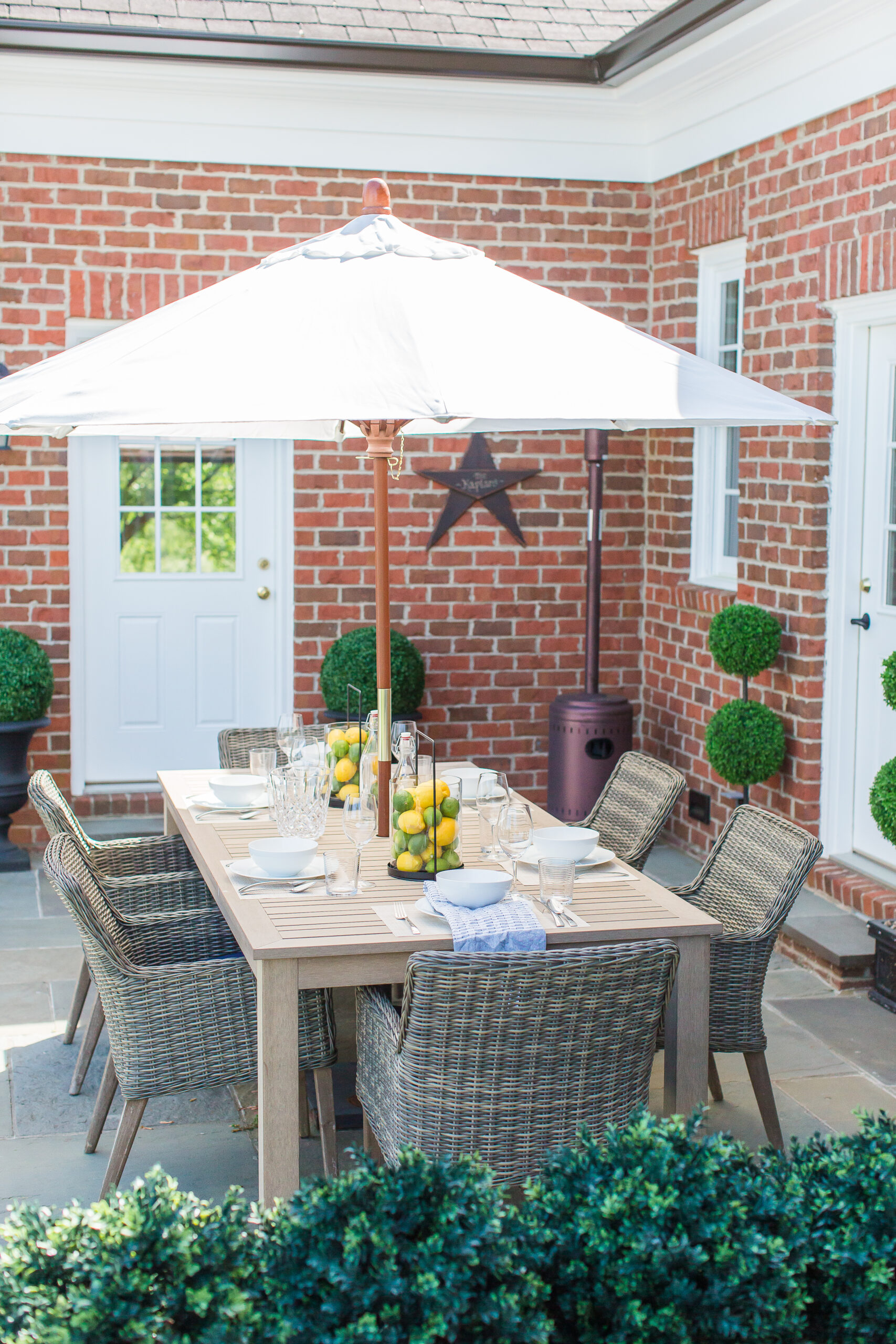 outdoor patio dining table styling with a patio umbrella, wicker patio chairs, artificial lemons and limes decorated in candle lanterns
