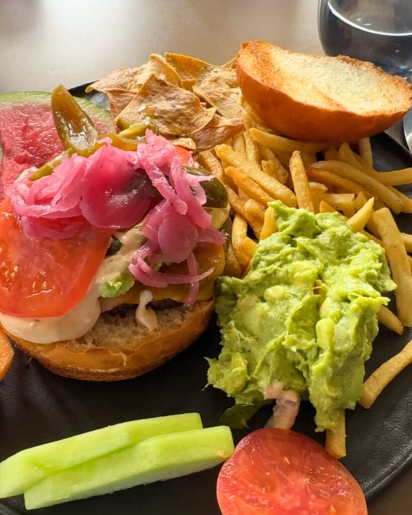 A cheeseburger that you can barely see through the toppings and guacamole.
