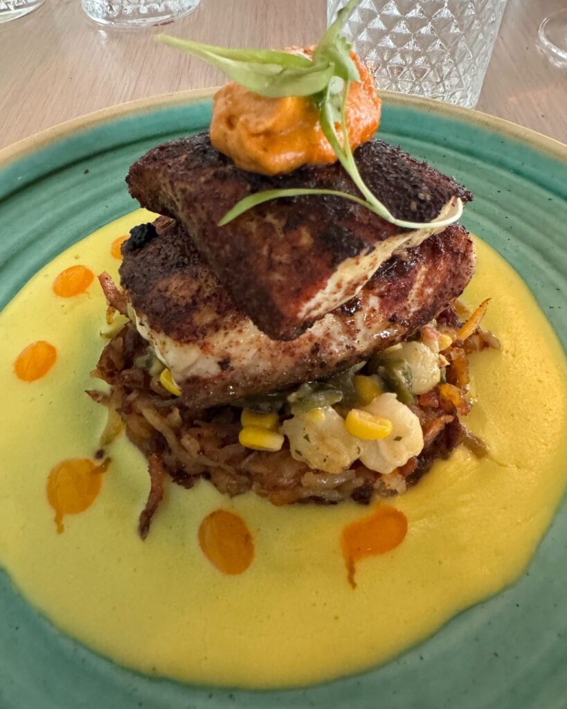 Blackened Redfish with chorizo-sunchoke hash, sweet corn hominy, and red pepper rouille
